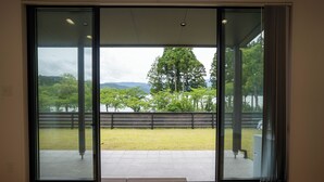 Une pièce dotée d’une grande porte-fenêtre coulissante qui donne sur un espace extérieur avec une pelouse et des arbres.