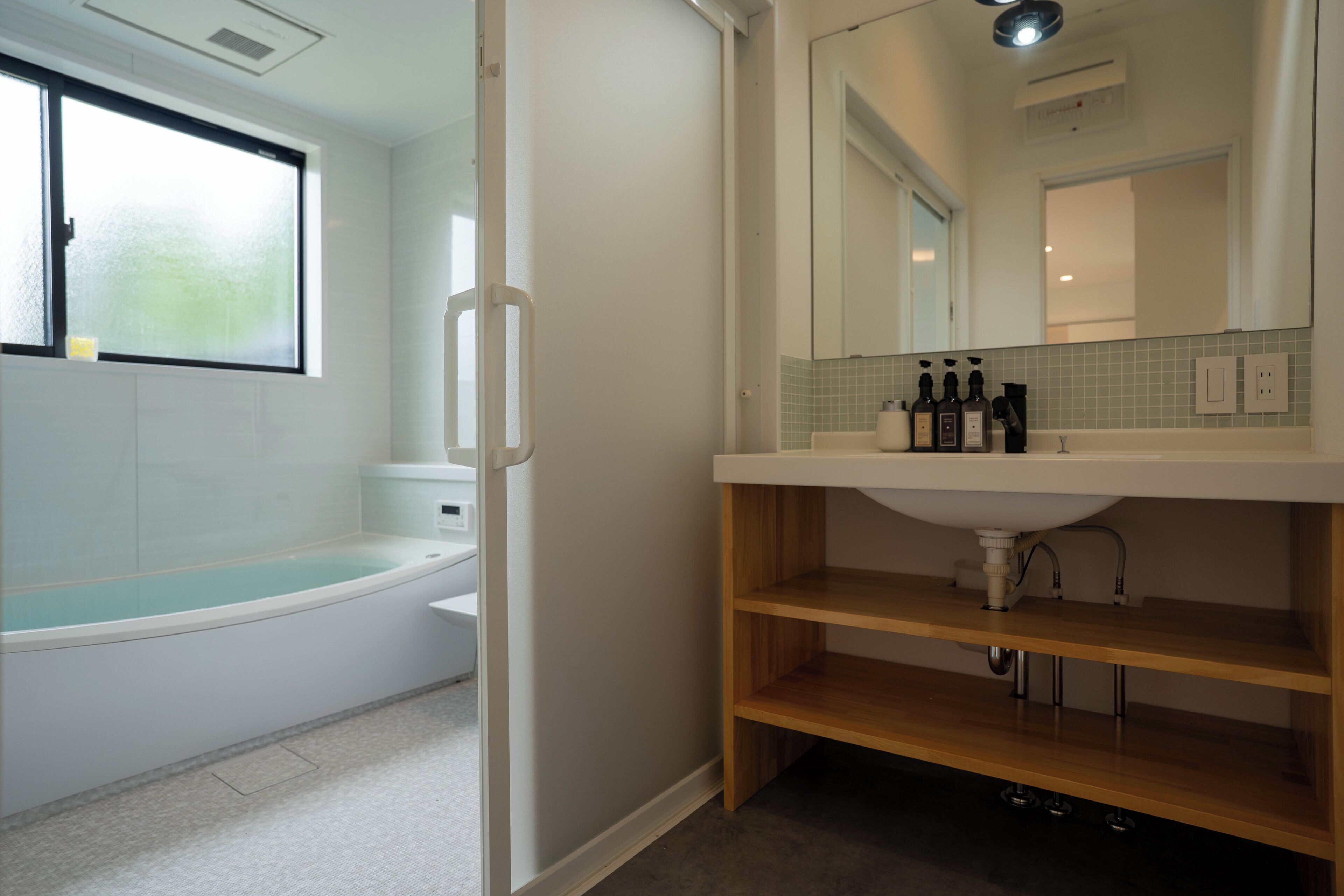 Un baño moderno con una bañera, un tocador con espejo y una estantería.