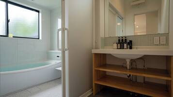 Un baño moderno con una bañera, un tocador con espejo y una estantería.