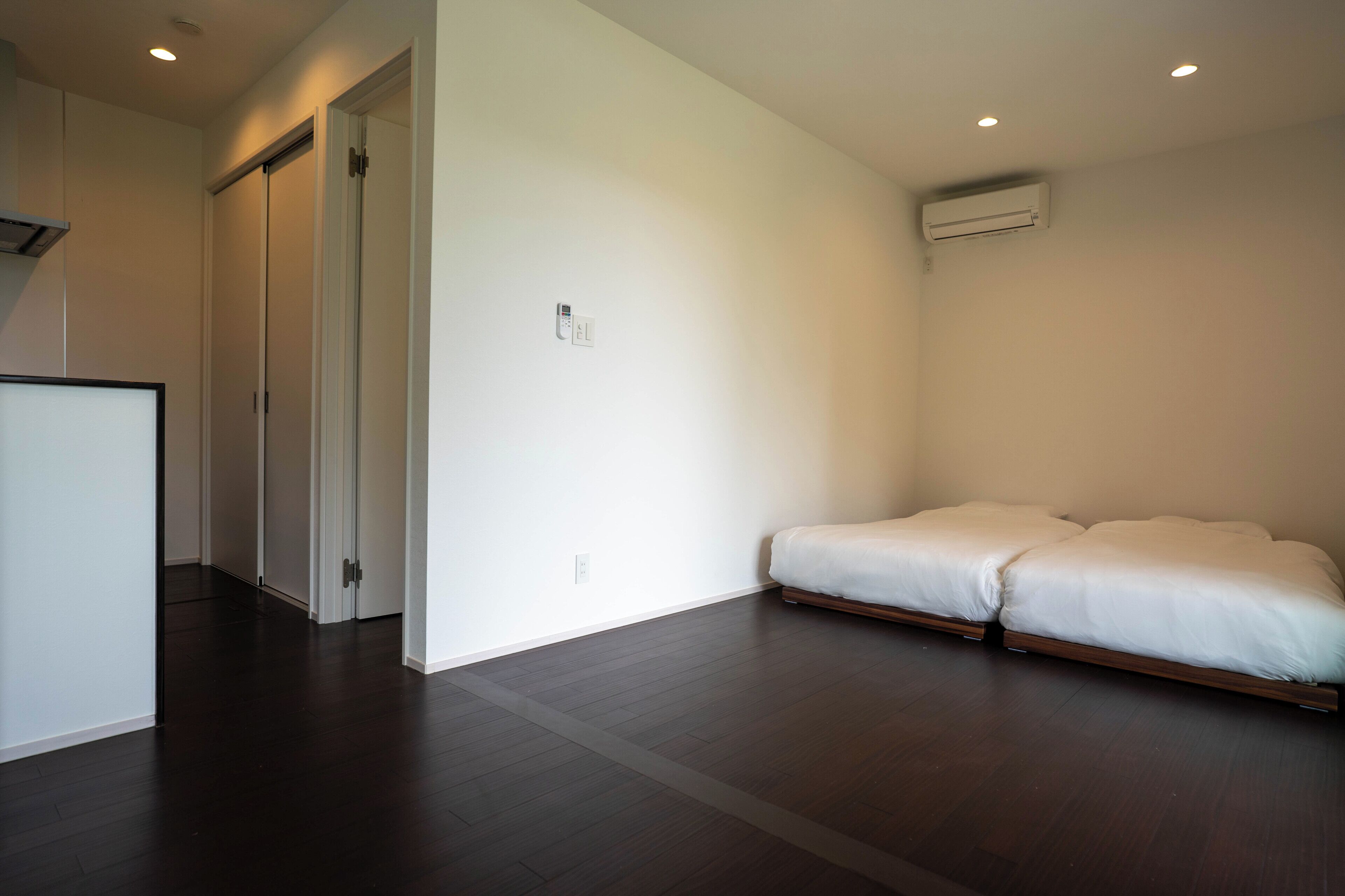 A room with a bed, a door, and an air conditioning unit.
