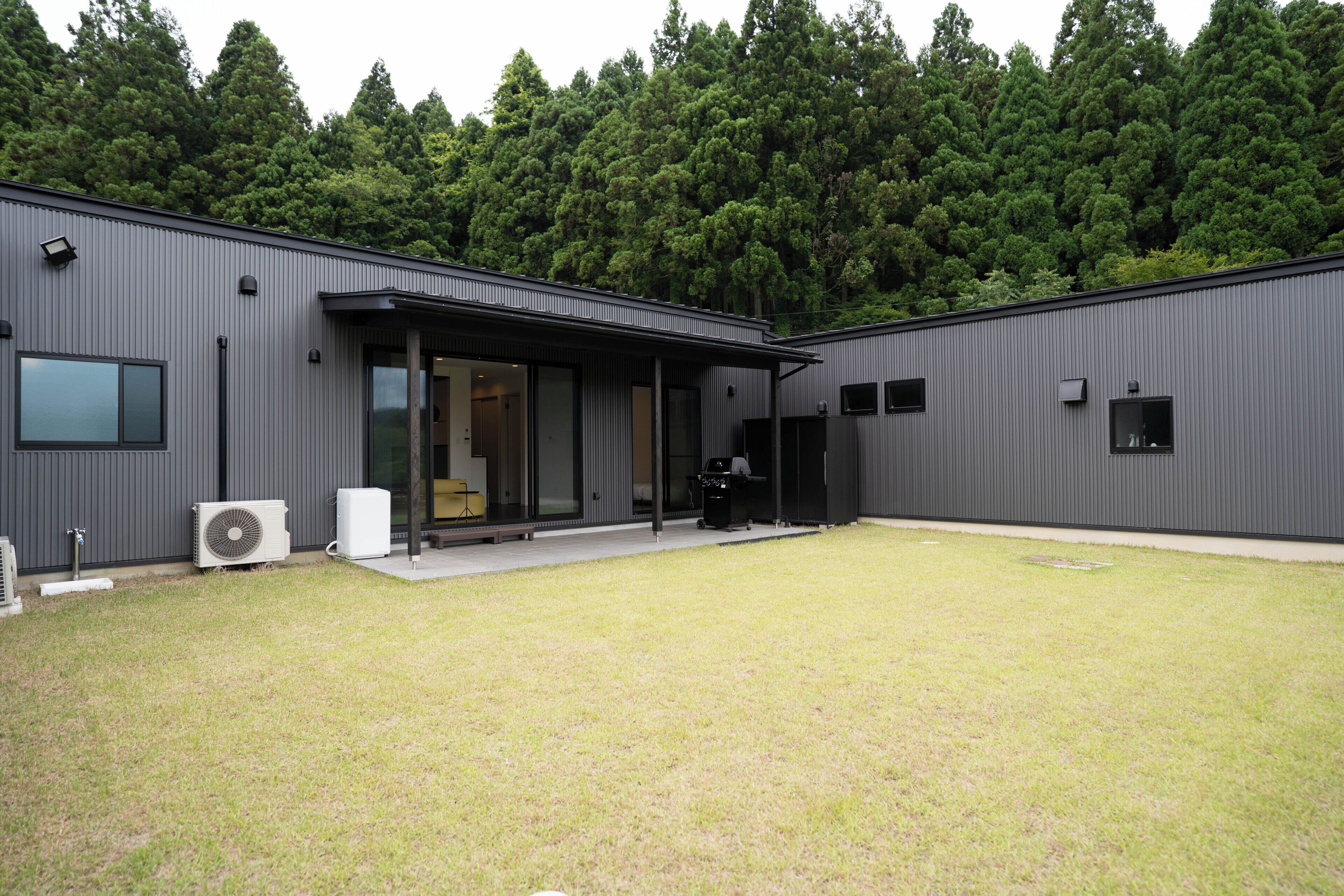 A modern building with a covered patio area, large windows, and an air conditioning unit.