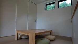 Une pièce avec une table en bois, des tatamis et une fenêtre.