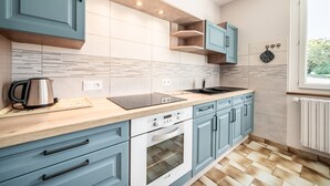 Cozinha moderna com armários azul-claros, bancada preta e janela que traz luz natural.