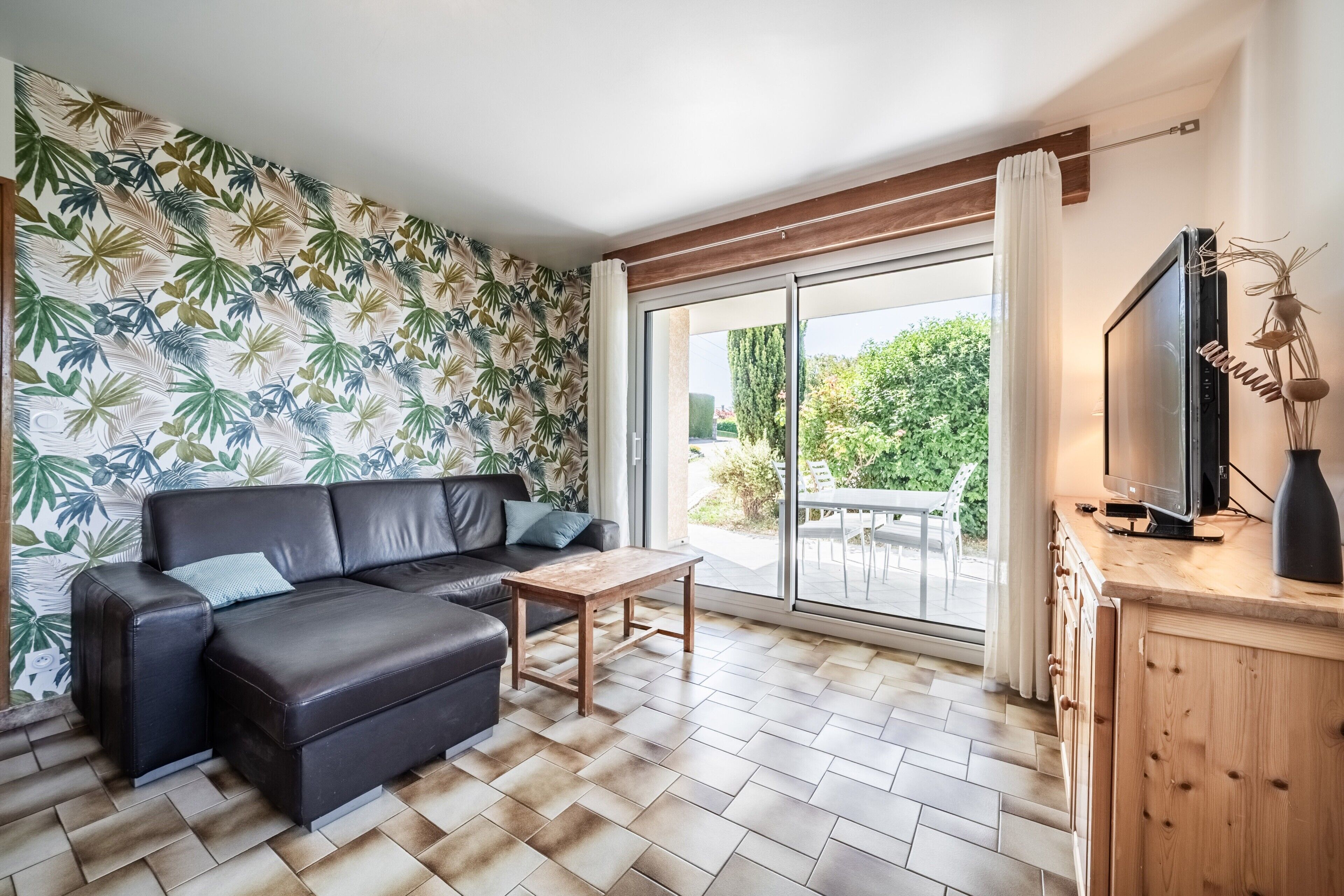 Una sala de estar moderna con un sofá modular, una mesa de centro y un televisor sobre un mueble de madera.