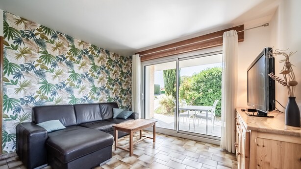 Uma sala de estar moderna com um sofá seccional, uma mesa de centro e uma televisão sobre um aparador de madeira.