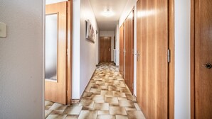 Um corredor com portas de madeira, piso estampado e iluminação no teto.