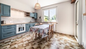 Uma cozinha com armários verde-água, piso de madeira e uma mesa de jantar para quatro pessoas.