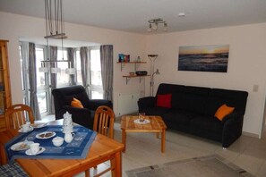 Ein Wohnzimmer mit Esstisch, zwei Sofas, einem Couchtisch und einem Gemälde an der Wand.
