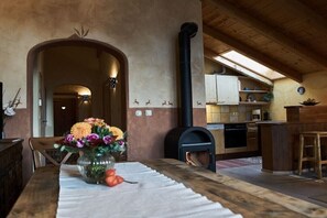 A rustic kitchen with a wood-burning stove, a dining area with a vase of flowers, and a kitchen island. - Holiday apartment with 2 bedrooms (Bischofswiesen)