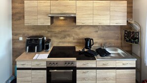Cozinha moderna com armários de madeira, forno embutido, cafeteira e pia.