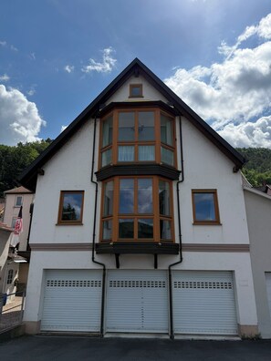 Ein zweigeschossiges Gebäude mit Erkerfenster und Garage mit Rolltor, bewölkter Himmel.
