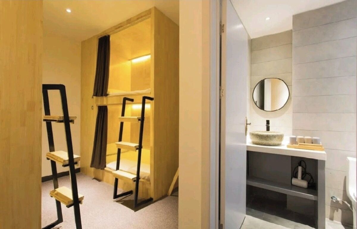 A modern bathroom with a round mirror, a sink, and a shelf with toiletries.