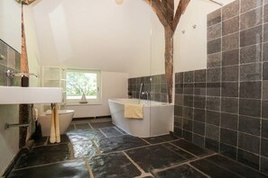 Ein Badezimmer mit Badewanne, Toilette und Fenster.