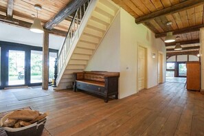 Ein geräumiger Raum mit Holzdielen, einer Treppe, einer Bank und einer Tür zu einem weiteren Bereich.