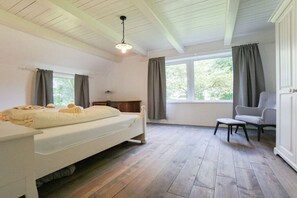 Una habitación con cama, sillón, ventana y lámpara en el techo.