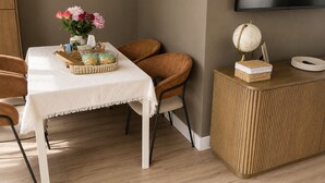 A dining area with a table set for two, a globe on a sideboard, and a TV mounted on the wall. - Modern Gated Retreat | Secure Parking & Patio | Great transport links (Croydon)
