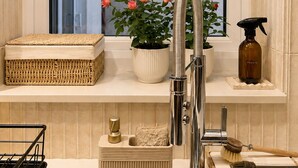 A modern bathroom with a built-in sink, a window with a view of greenery, a potted plant, and a spray bottle. - Modern Gated Retreat | Secure Parking & Patio | Great transport links (Croydon)