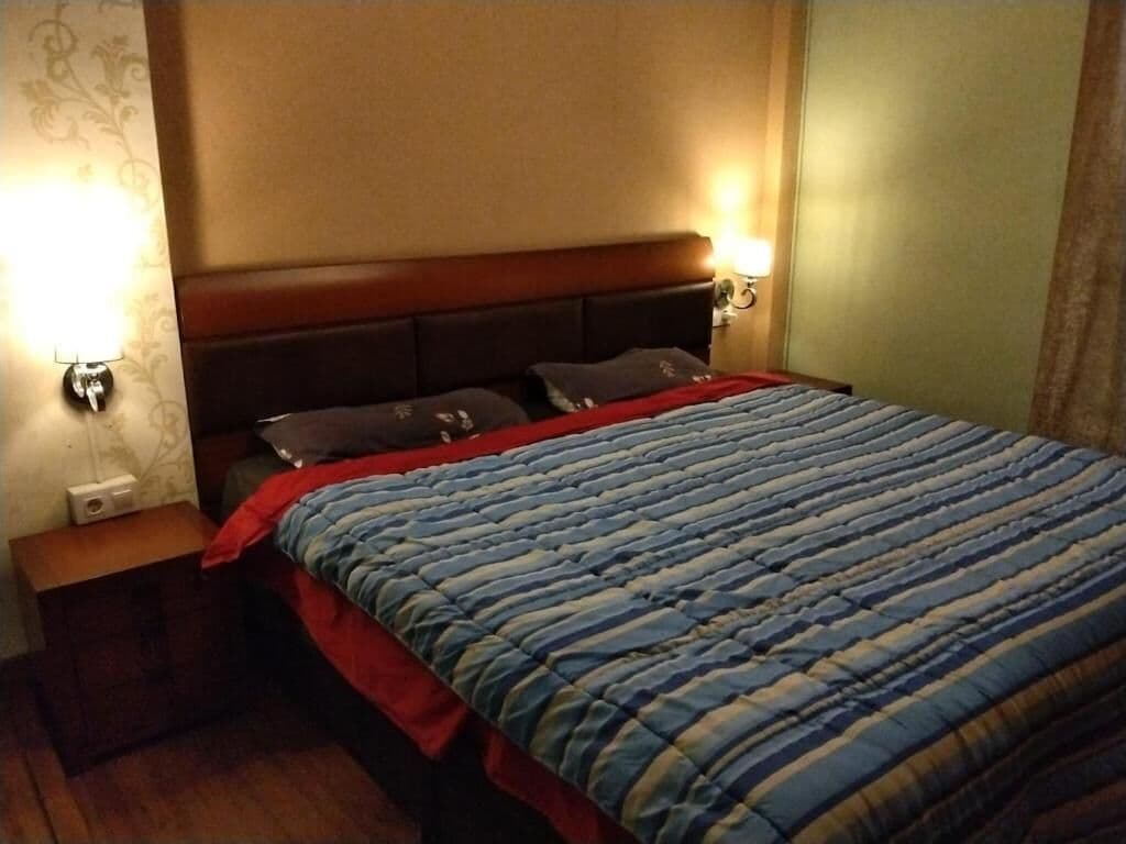 Een hotelkamer met een bed, nachtkastjes en wandlampen.