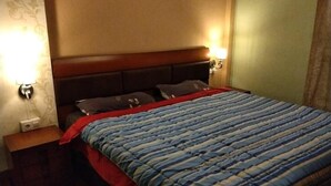 Ett hotellrum med en säng, sängbord och väggmonterade lampor.