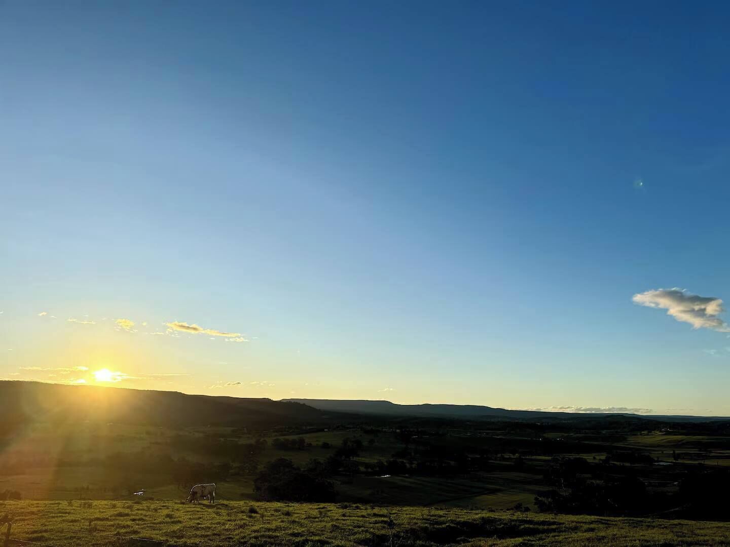A rural landscape with rolling hills and a clear sky.