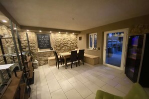 A dining area with a stone wall, a chalkboard with text, and a sliding glass door leading outside. - Holiday home in Uelversheim with Wi-Fi (Uelversheim)