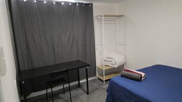 A room with a bed, a desk, a chair, a wardrobe, and a curtain.