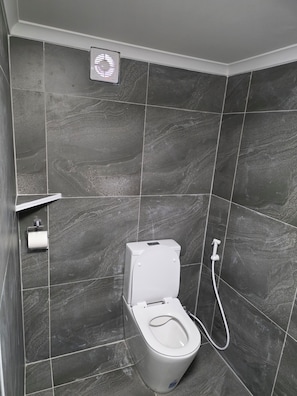 A bathroom with a toilet, a hand dryer, and a showerhead. - Sansa Farmhouse (Kelmscott)