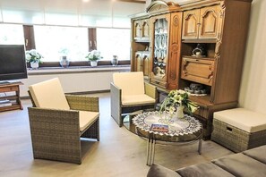 A living room with wicker furniture, a glass coffee table, and a wooden cabinet with decorative items. - Holiday apartment with 3 bedrooms (Sinspelt)
