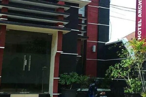 A hotel with a modern facade, a prominent vertical sign, and a well-maintained entrance area. - Cozzy Hotel Archie 2 (Ternate)