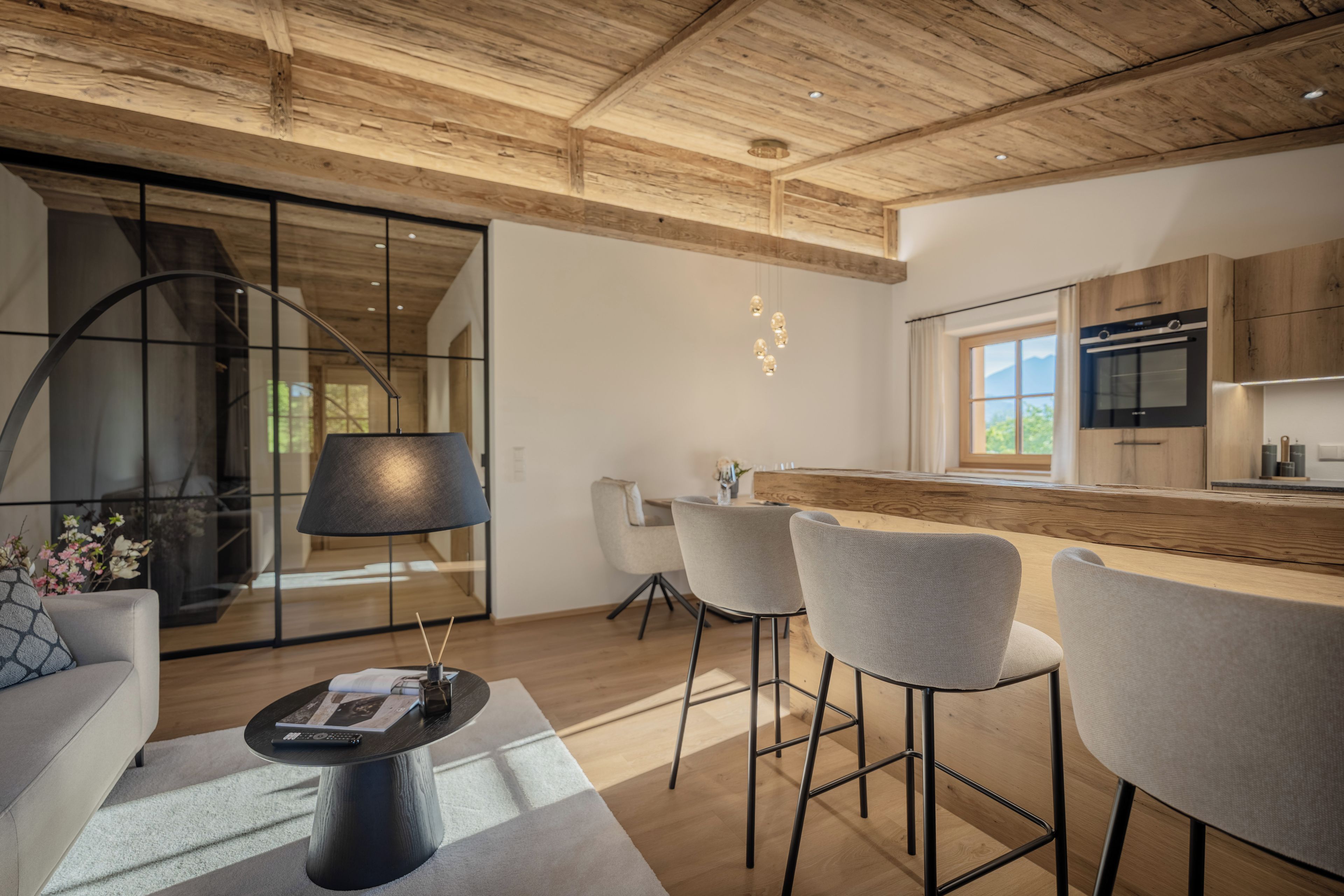 A modern kitchen with wooden cabinetry, a built-in oven, and a large window.
