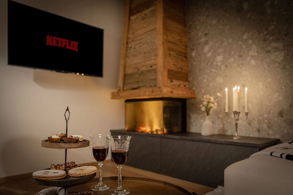 A cozy room with a fireplace, a Netflix TV, and a tray with pastries and drinks.