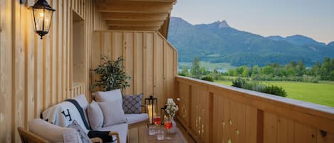Una terraza de madera con un sofá, una mesa y una planta en maceta.