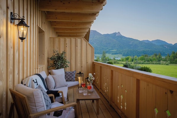Una terraza de madera con un sofá, una mesa y una planta en maceta.