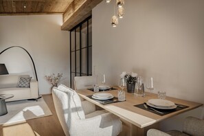 Et spiseområde med et træbord dækket til fire personer, inklusive tallerkener, glas og bestik.