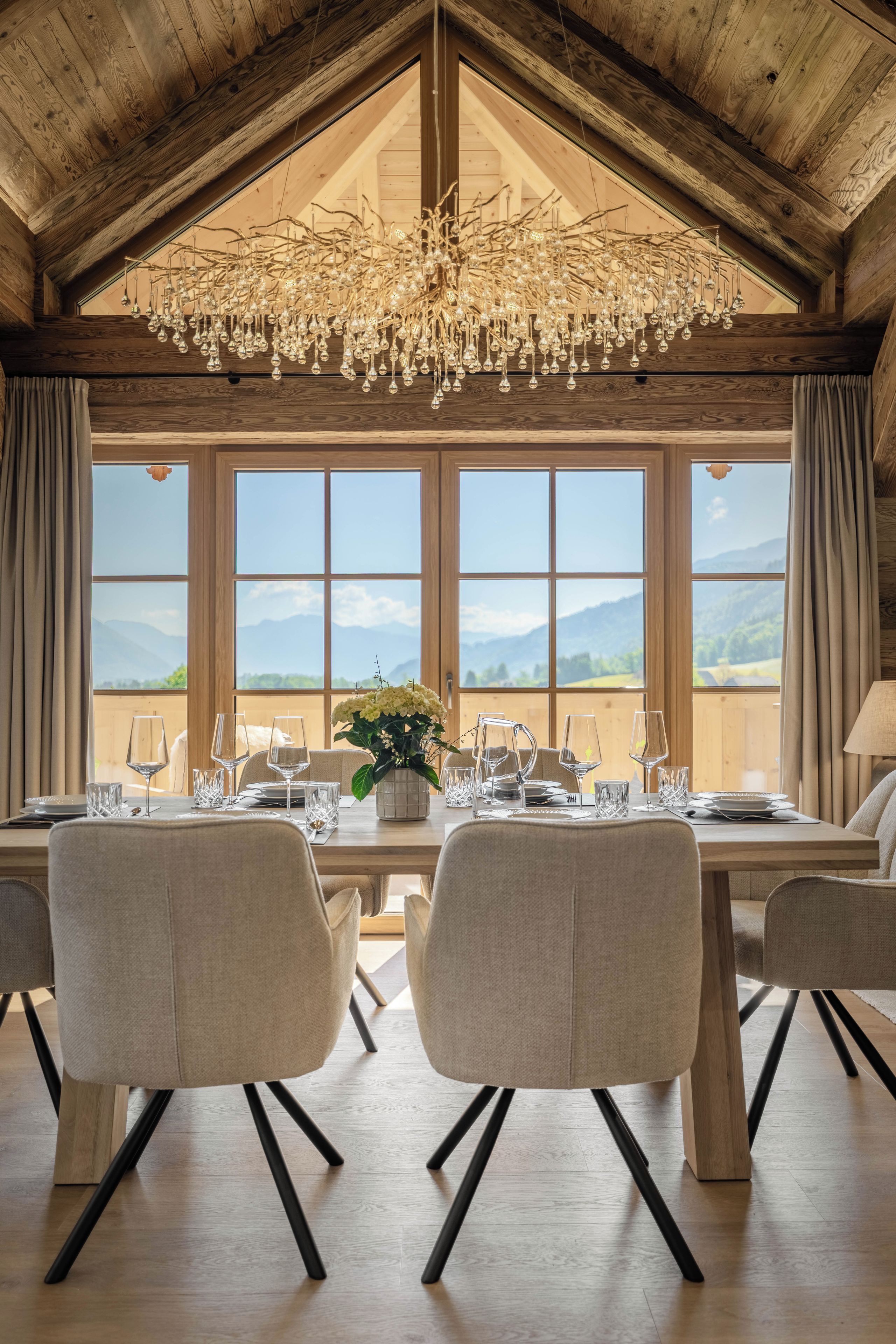 A dining area with a high ceiling, a chandelier, and a table set for four with chairs.