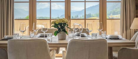 A dining area with a high ceiling, a chandelier, and a table set for four with chairs.