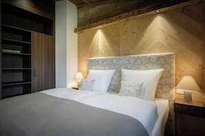 Ein Schlafzimmer mit einem großen Bett, einem Holz-Kopfteil, Nachttischlampen und einem eingebauten Kleiderschrank.