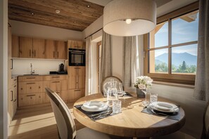 Eine moderne Küche mit Holzausstattung, einem eingebauten Backofen und einer Essecke mit Tisch für zwei Personen.