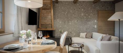 A modern living room with a fireplace, a round dining table set for four, and a comfortable sofa.