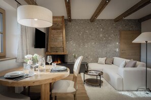 Ein modernes Wohnzimmer mit Kamin, einem runden Esstisch für vier Personen und einer bequemen Couch.
