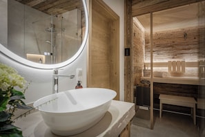 Ein modernes Badezimmer mit einem großen, ovalen Waschbecken, einem runden Spiegel und einer Holzvertäfelung.