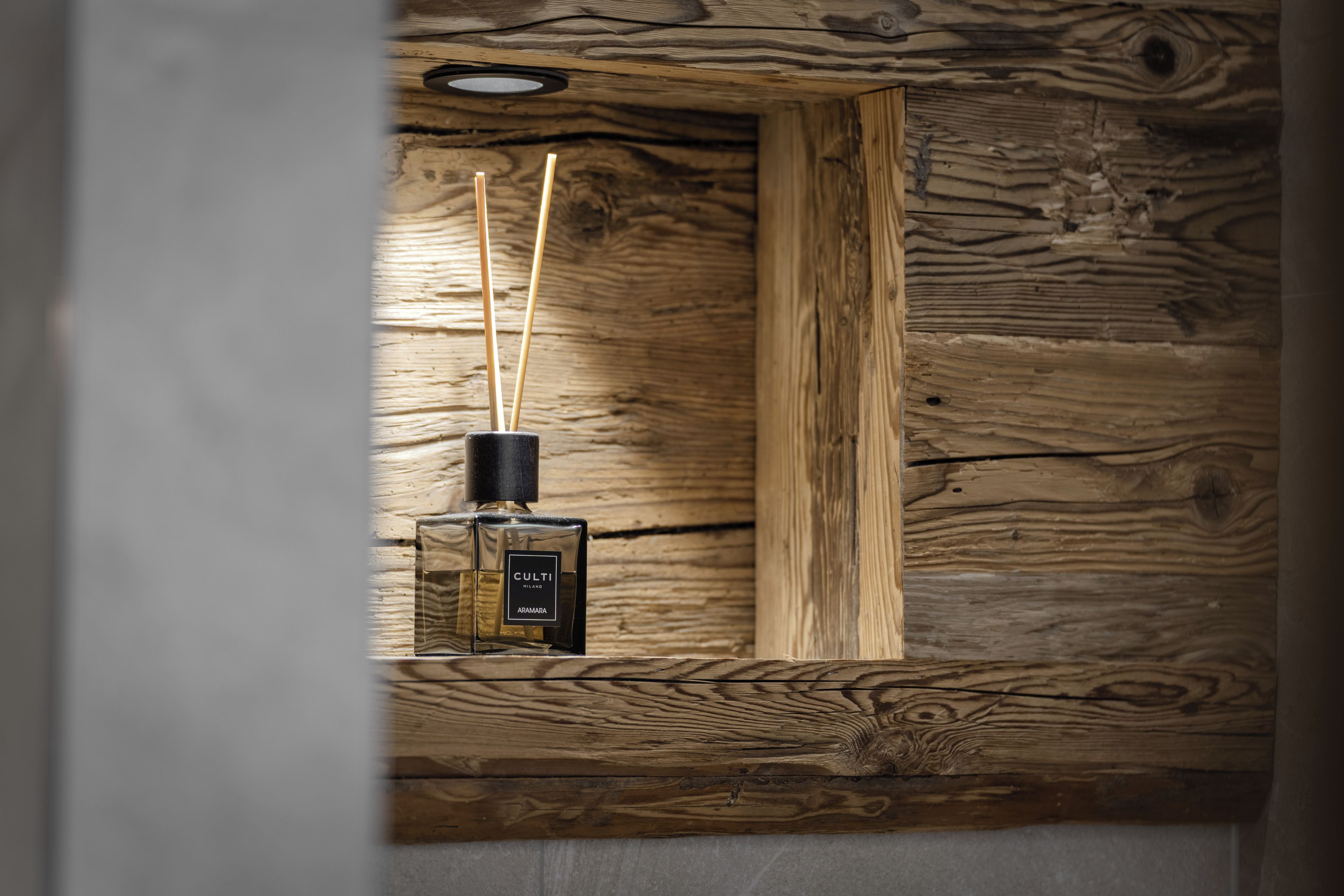 A wooden wall with a black bottle and two sticks.