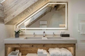 Ein Badezimmer mit Holzboden, einem großen Spiegel, zwei Waschbecken und einem Handtuchhalter.