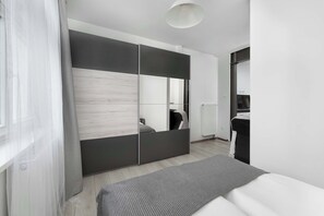 Een moderne slaapkamer met een bed, een grote kledingkast en een radiator.