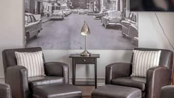 A living room with a large vintage street scene poster, leather sofas, a small side table, and a coffee table.
