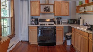 A kitchen with wooden cabinets, a stove, a microwave, and a refrigerator. - Historic Main St. Rosendale Apt (Rosendale)