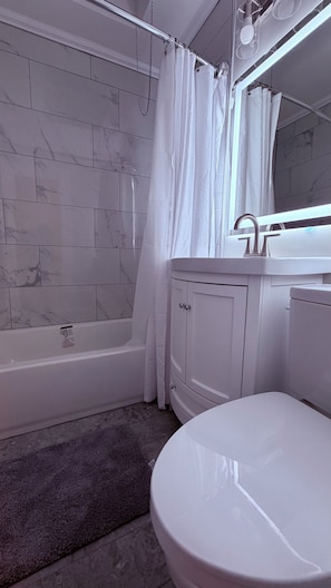Ein Badezimmer mit einer weißen Badewanne, einer Toilette und einem Waschtisch mit Spiegel.