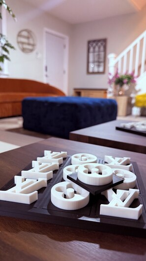Ein Wohnzimmer mit einer Couch, einem Couchtisch mit 3D-gedruckten Objekten, einer Treppe und einer Tür im Hintergrund.