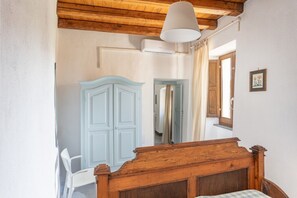 A bedroom with a wooden ceiling, a white wardrobe, a bed with a wooden headboard, and a hanging light fixture. - Steinmelker House - Seneghe (Seneghe)