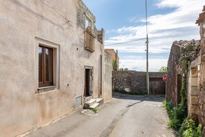 A narrow street with old buildings, a stop sign, and a stone wall. - Steinmelker House - Seneghe (Seneghe)